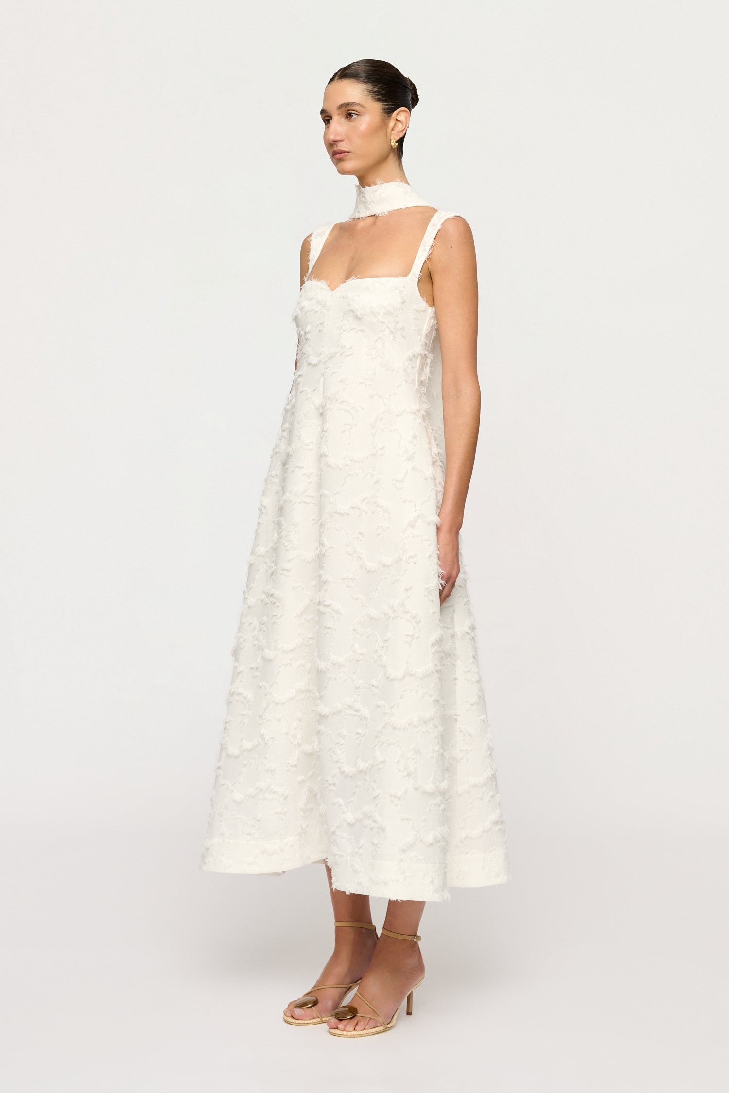Woman wearing a white Clea dress with floral textured details on a white background