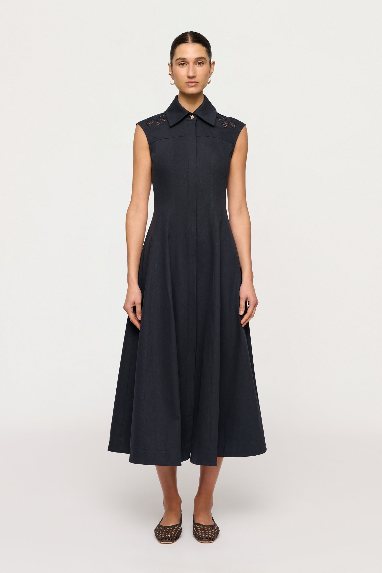 Woman wearing a black sleeveless dress with a collar on a white background