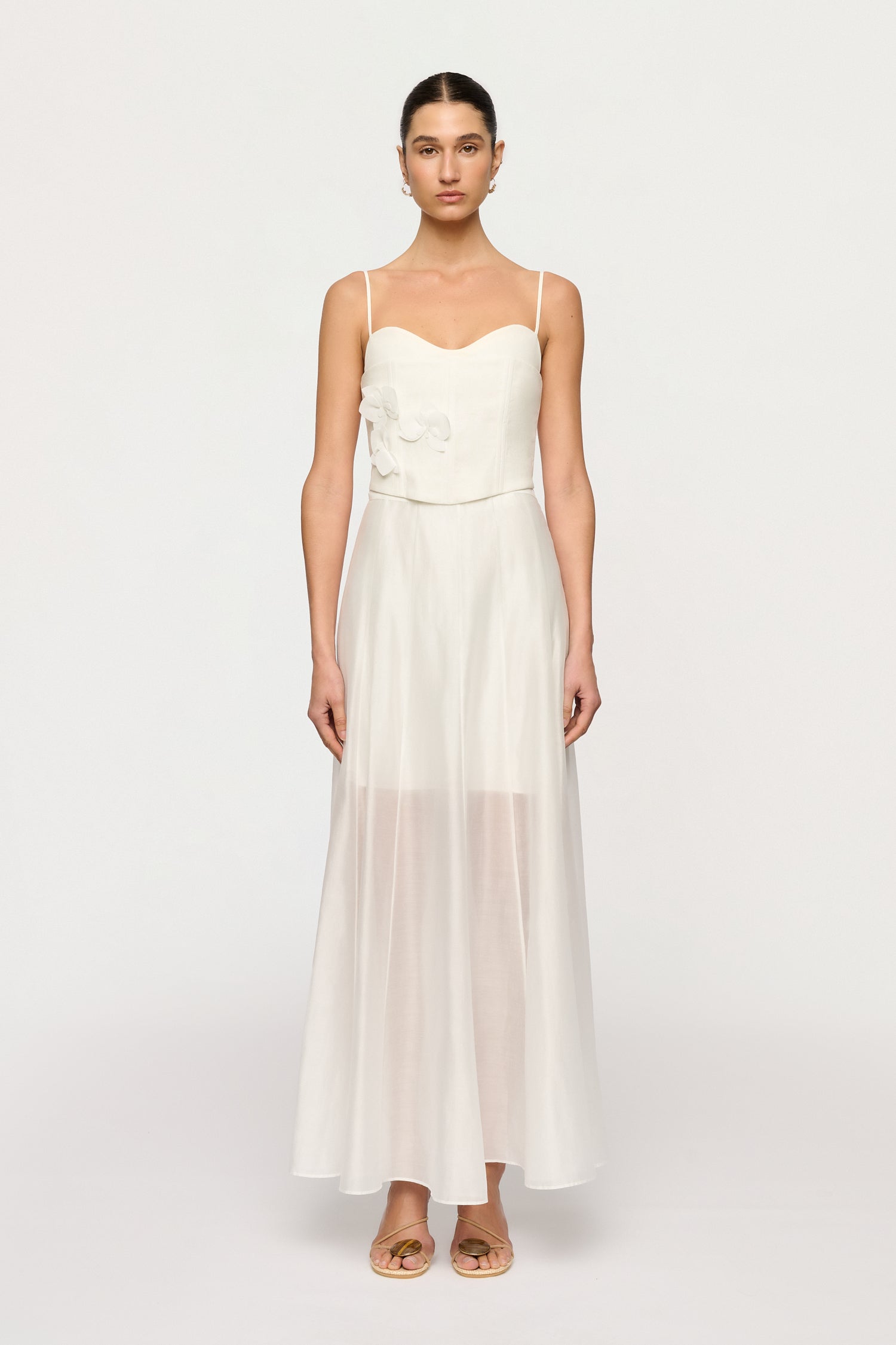 Woman wearing a white dress with floral details on a white background