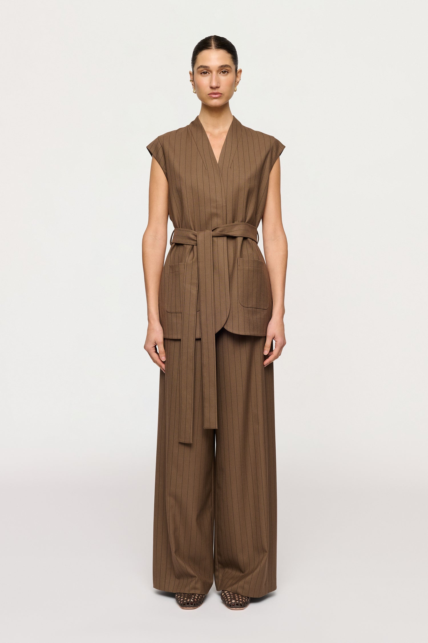 Woman wearing a brown sleeveless jumpsuit on a white background