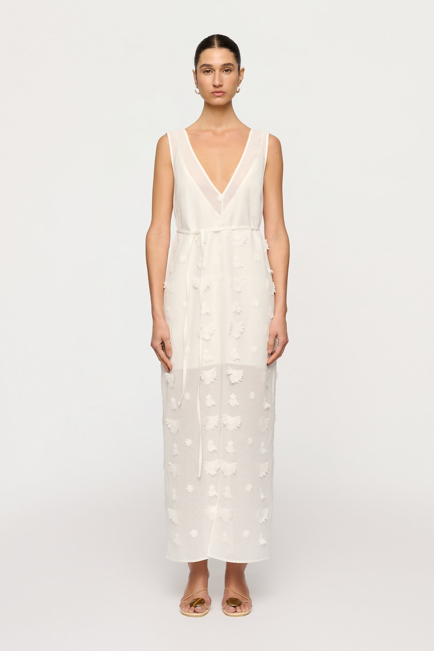 Woman wearing a white dress with a subtle pattern on a white background