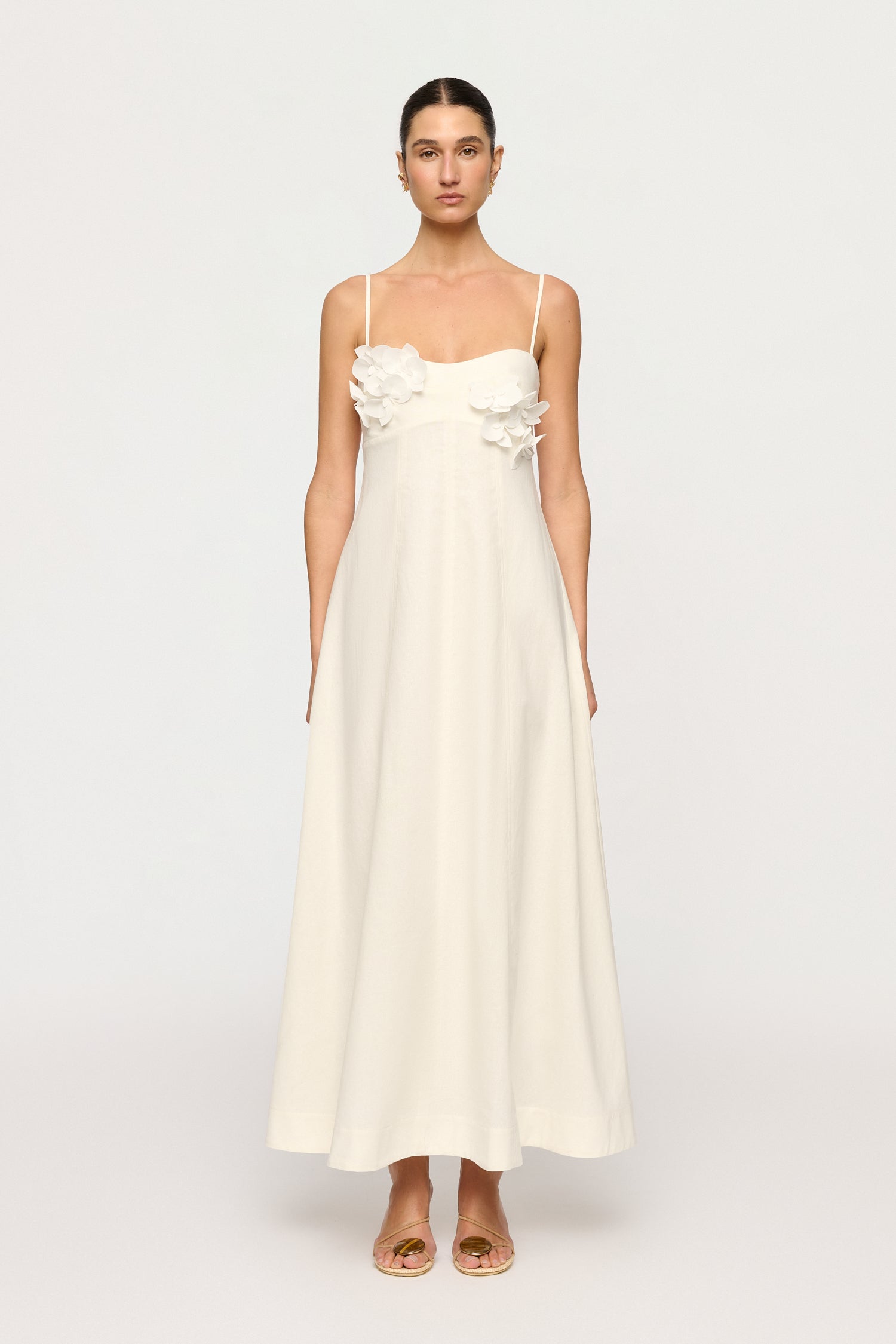 Woman wearing a white dress with floral details on a white background