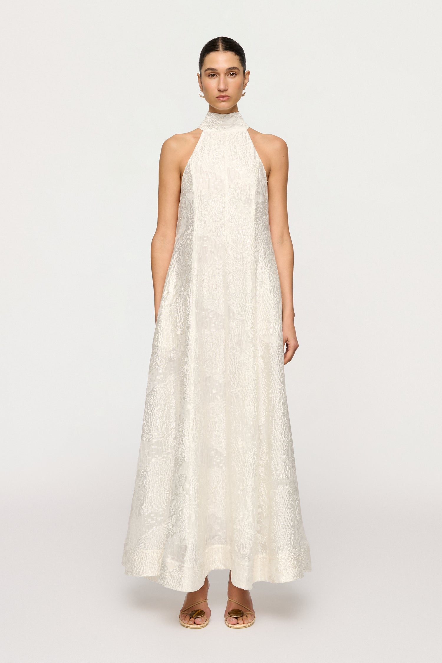 Woman wearing a white halter neck dress on a white background