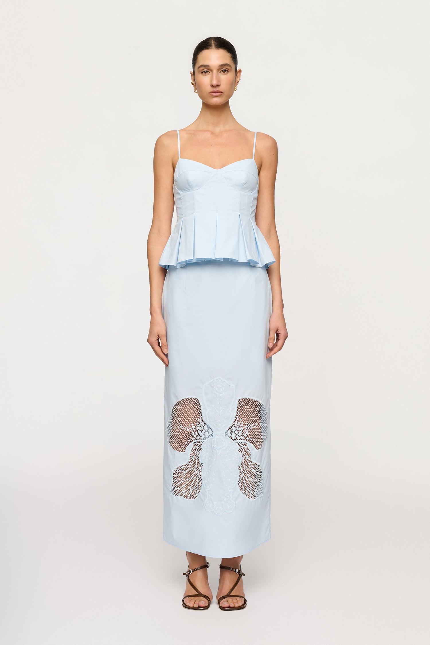 Woman wearing a light blue dress with a peplum top and lace detailing on a white background