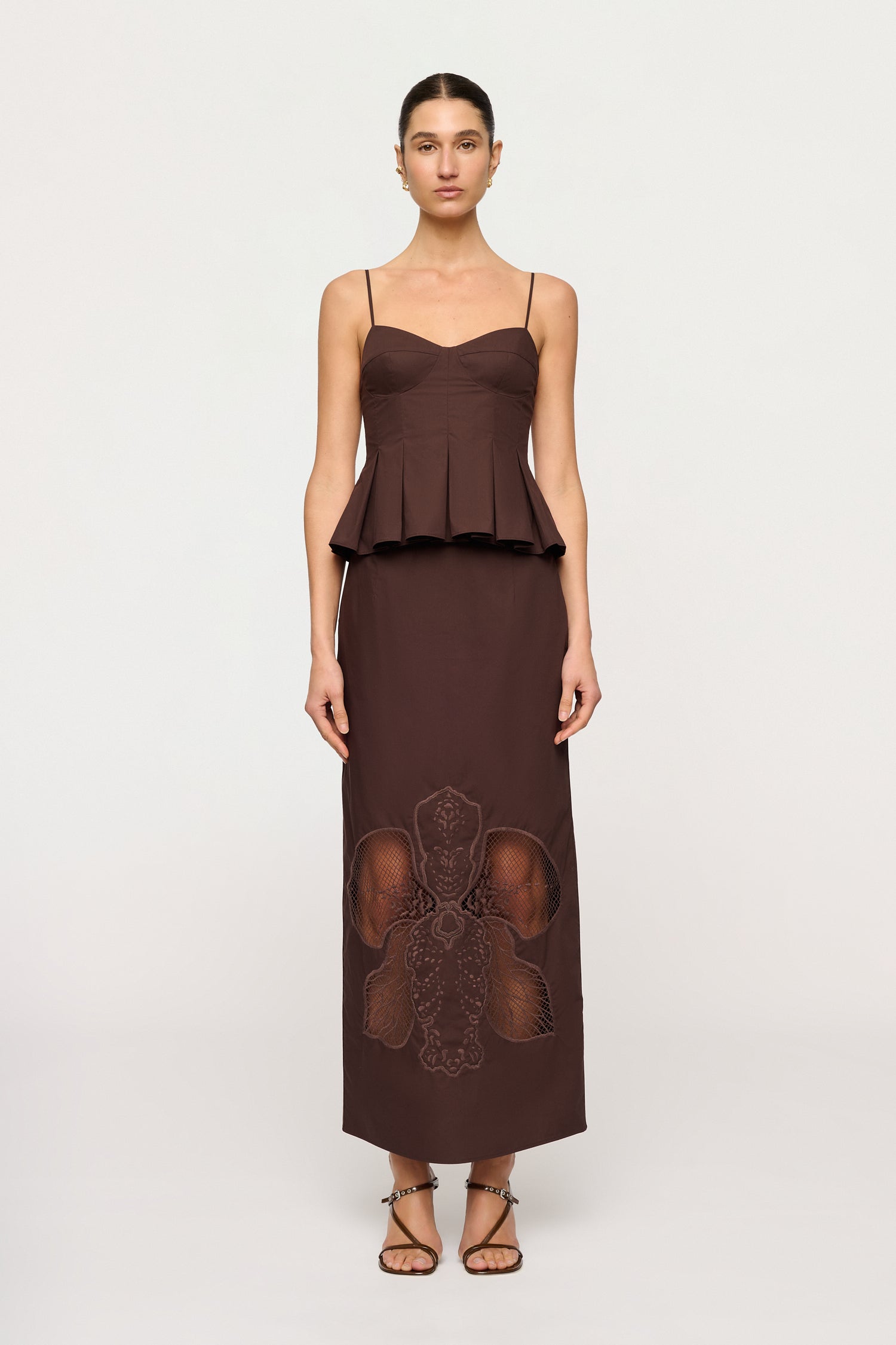 Woman wearing a brown dress with lace details on a white background